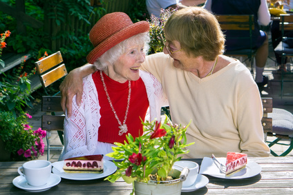Woman hugging laughing friend at lunch.
